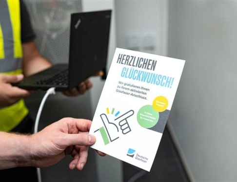 Mann hält Flyer zur Glasfaser in der Hand