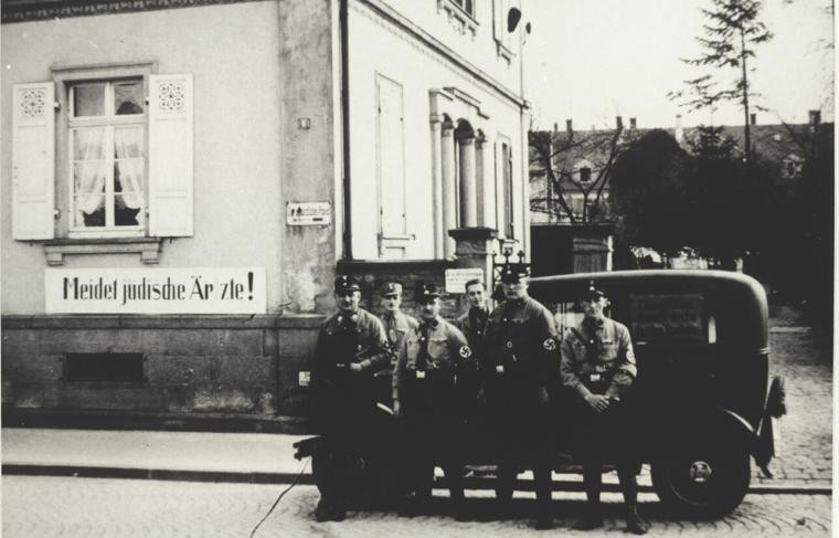 Des membres des SA se tiennent devant une voiture devant le cabinet du médecin Alfred Grünebaum