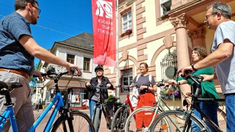 Group of cyclists in front of the Hisrorian town hall on the market square discussing the route