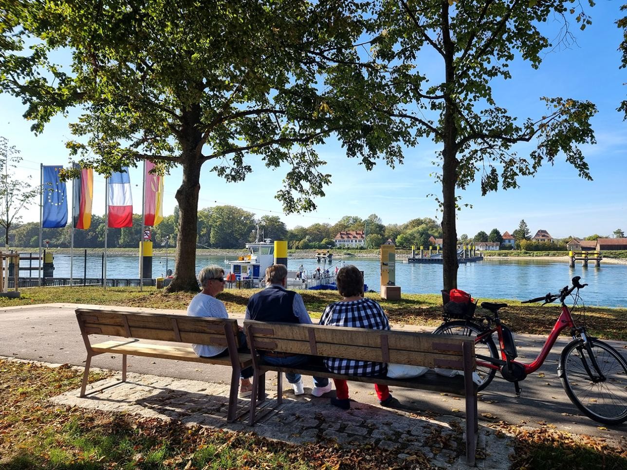 Rentner sitzen auf einer Bank an der Rheinpromenade