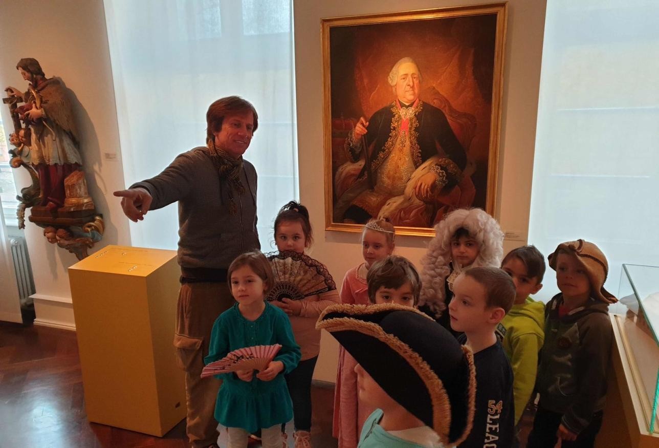 Museumspädagoge Eric Schütt umringt von Kindern im Stadtmuseum Rastatt.