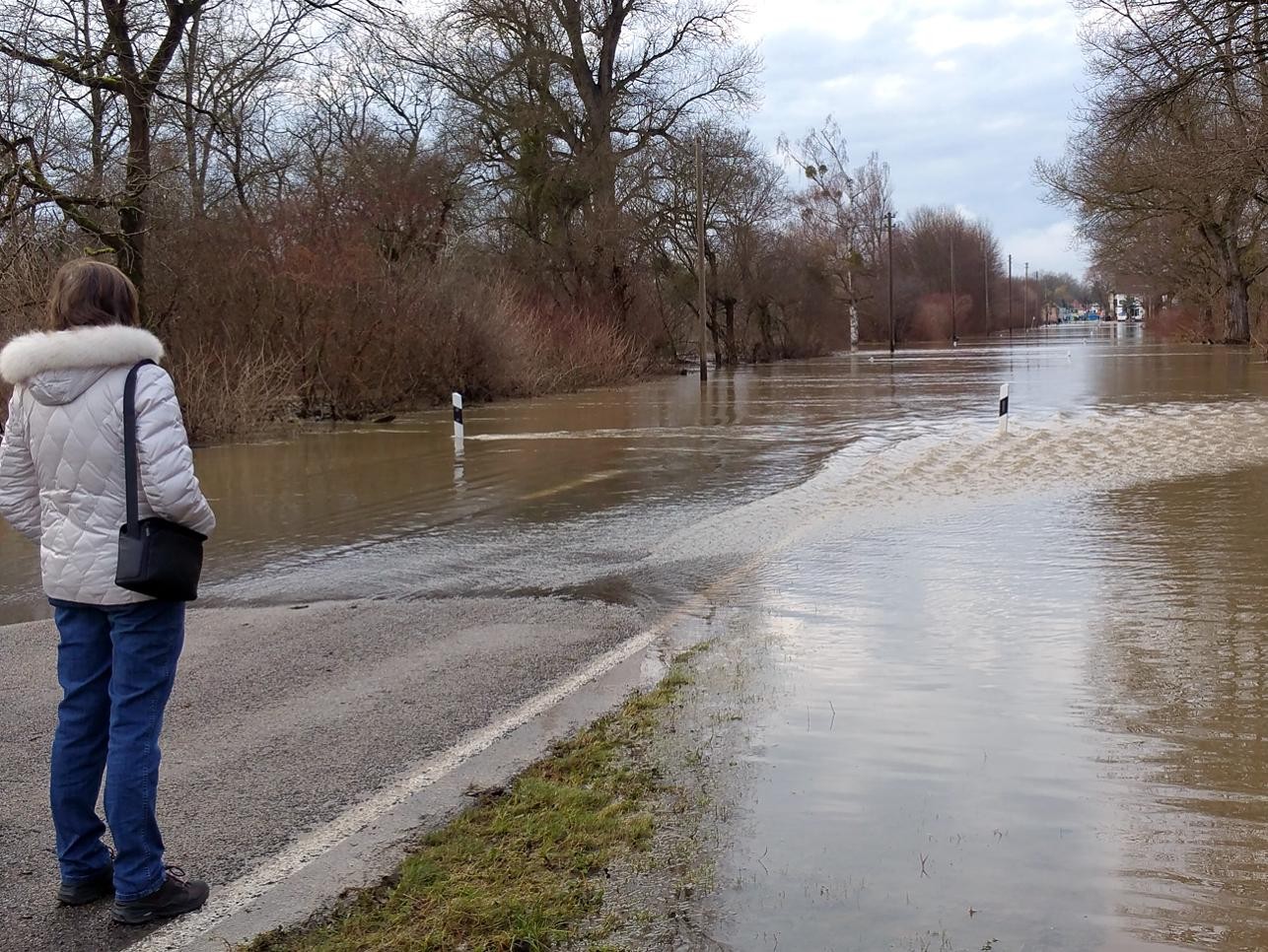 A woman stands at the flooded Fährstraße in Plittersdorf.