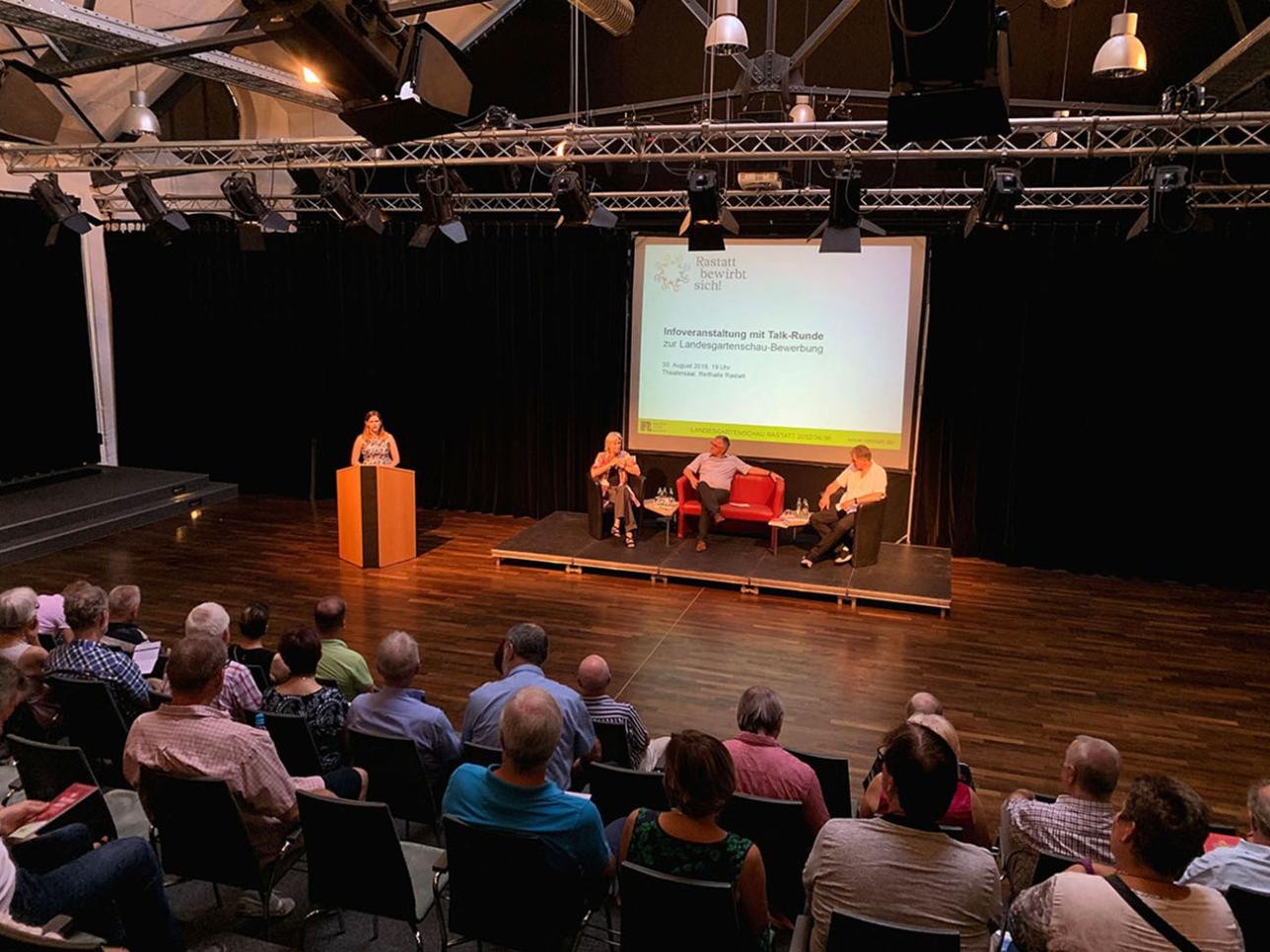 Information event on the Landesgartenschau application. Speakers sit on the stage and the audience is in the hall.
