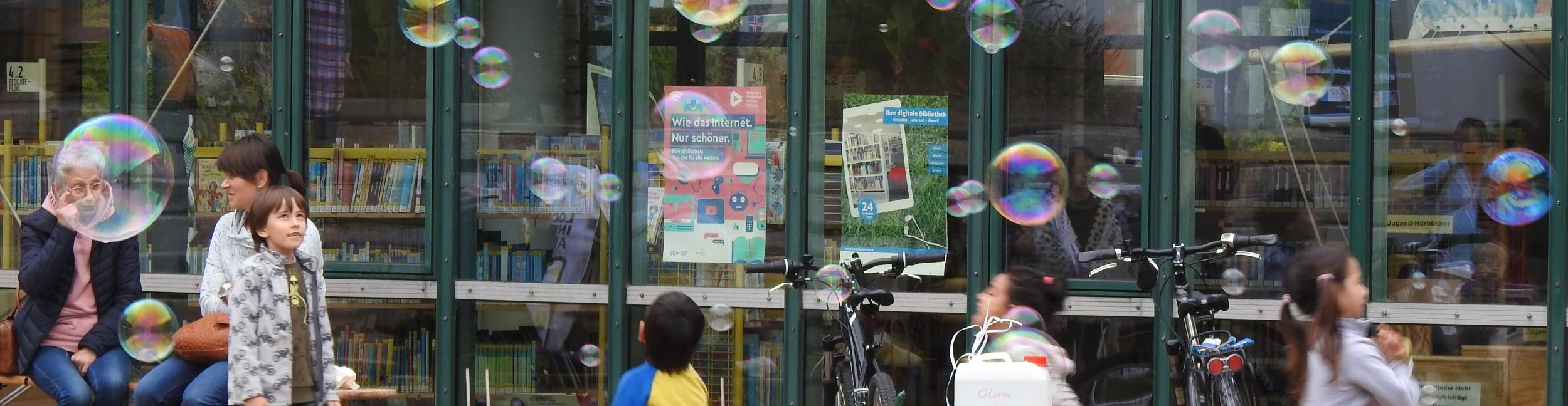 Children with soap bubbles in front of the library