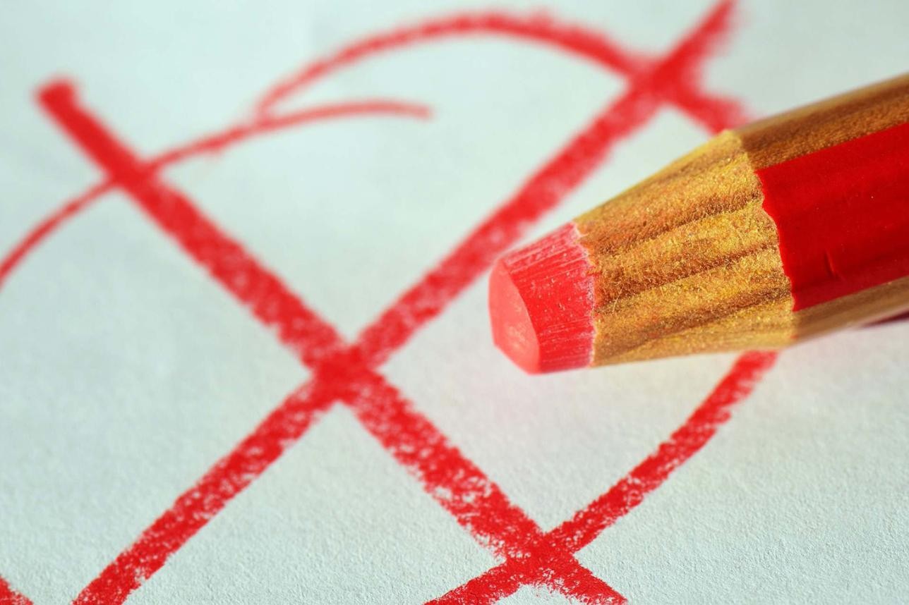 Une croix rouge dessinée au crayon de couleur avec un cercle autour et un crayon de couleur