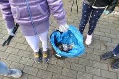 Kind hält Tüte mit eingesammelten Müll in der Hand.