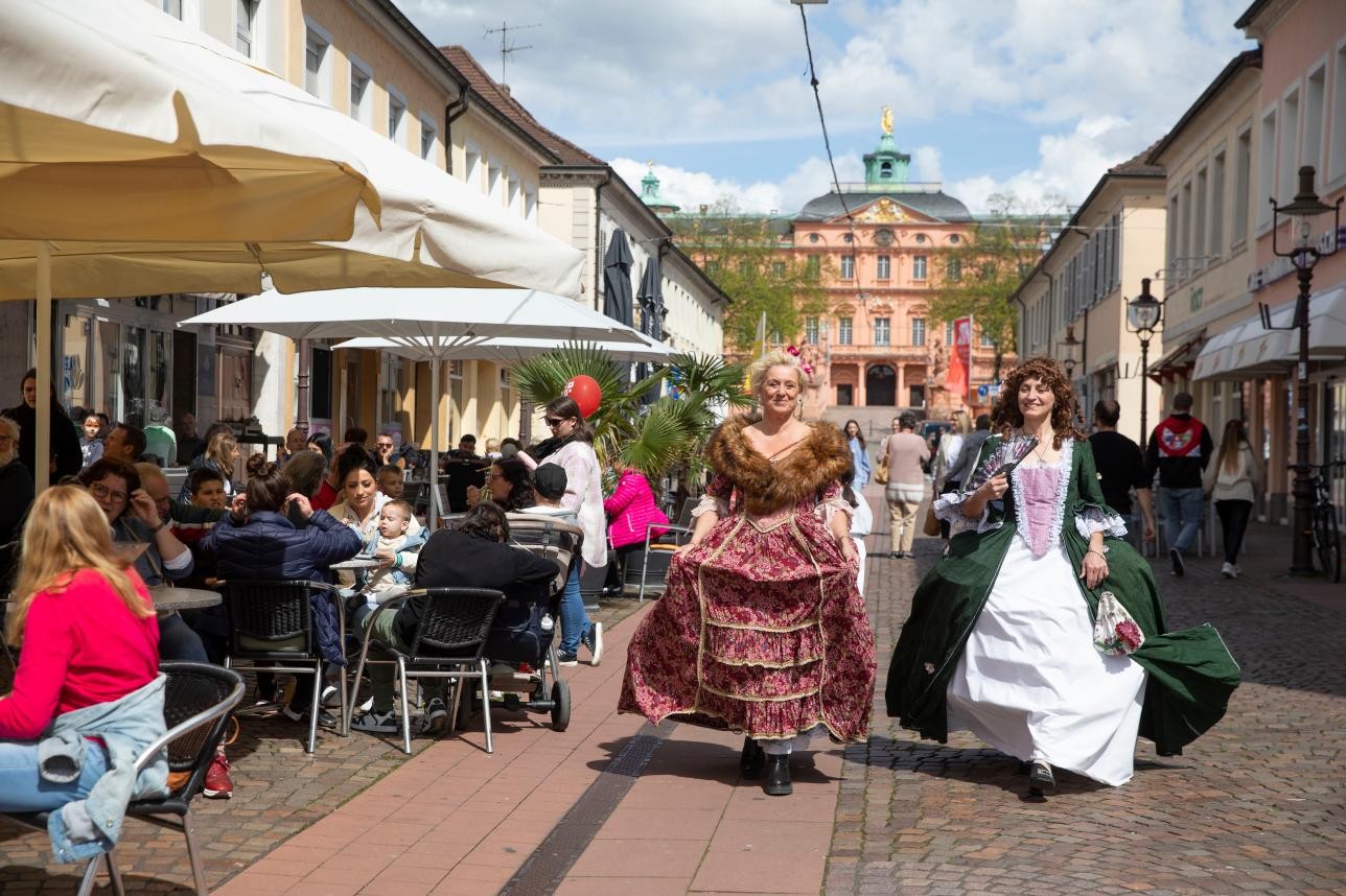 Zwei Frauen laufen verkleidet wie Hofdamen durch die Rastatter Innenstadt.