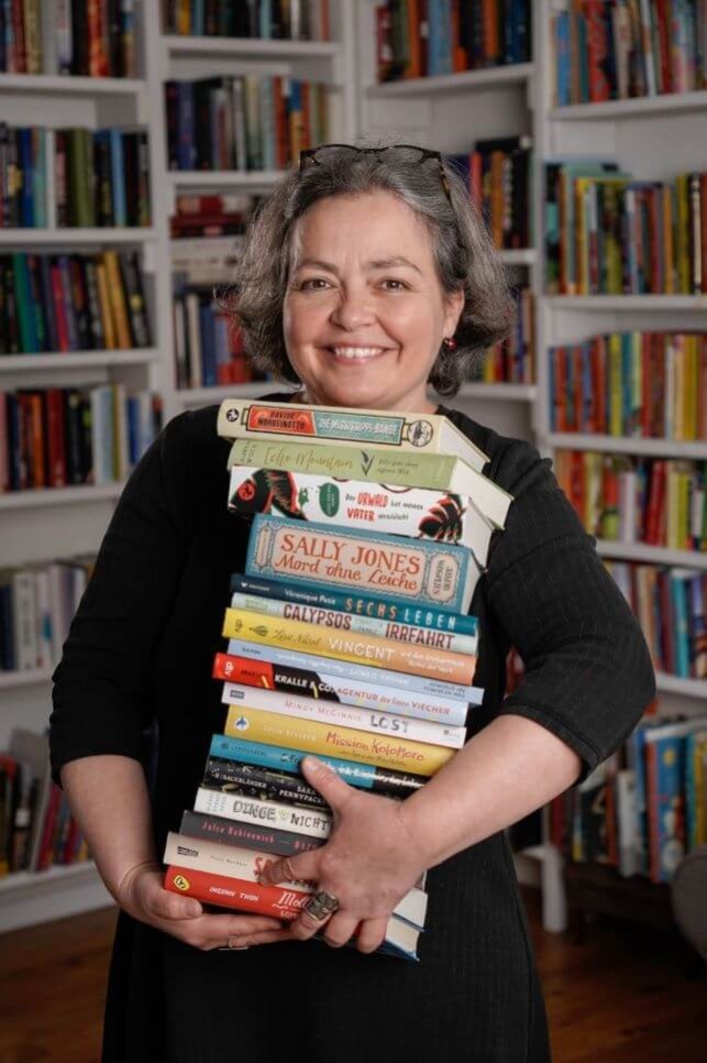 Frau hält mehrere Bücher im Arm 