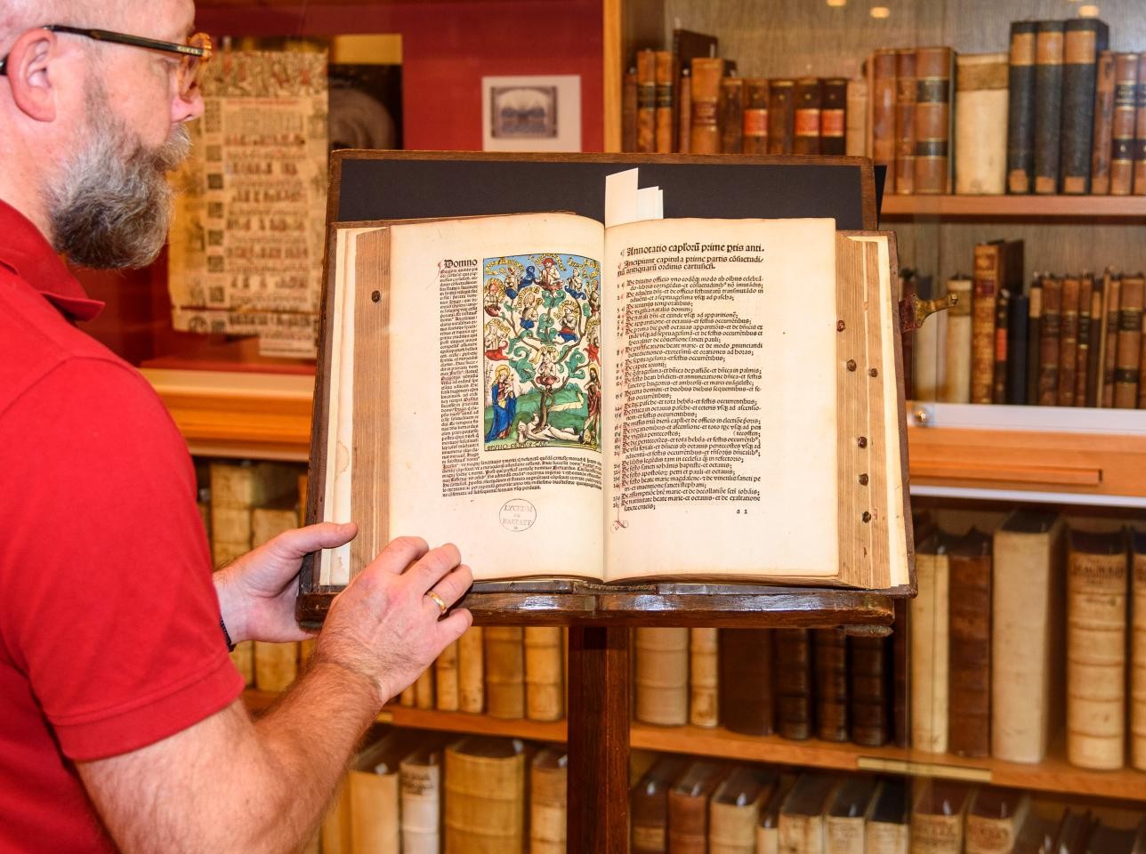Mann zeigt mittelalterliches Buch.