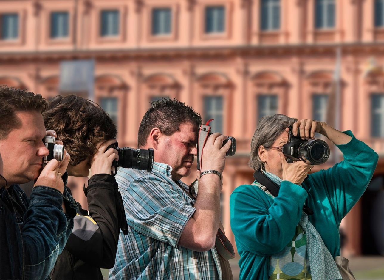 Viele Menschen mit einer Fotokamera vor dem Gesicht, im Hintergrund das Rastatter Residenzschloss.