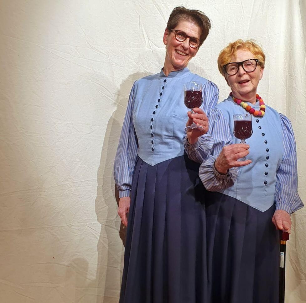 Zwei Frauen mit Weinglas auf der Bühne