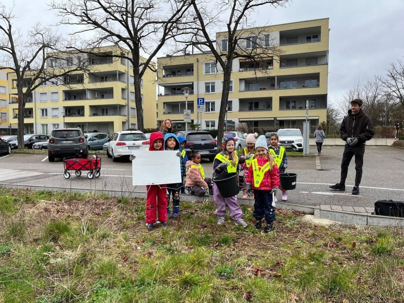 Kindergartenkinder beim Einsammeln von Müll auf Grünfläche 