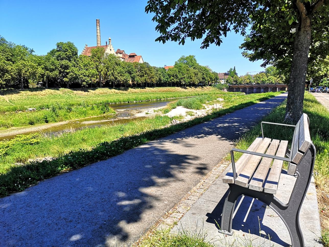 Weg auf dem Murgdamm mit einer Sitzbank gegenüber der Badner Halle