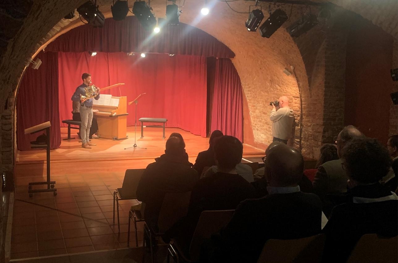 Man plays horn on stage in the Kellertheater with piano accompaniment