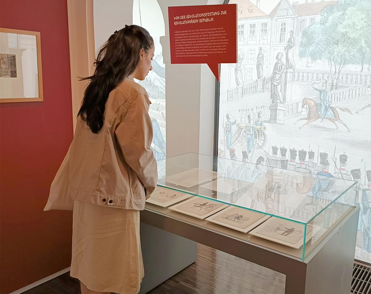 Une femme se tient devant une vitrine du musée municipal lors de l'exposition temporaire : "Pour la liberté ! Rastatt et la révolution de 1848/49"