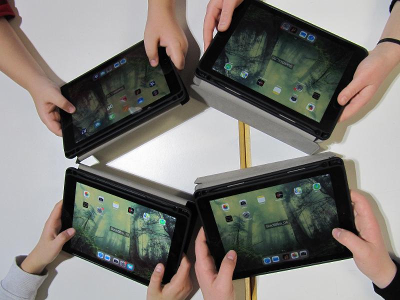 Vier Kinderhände halten iPads