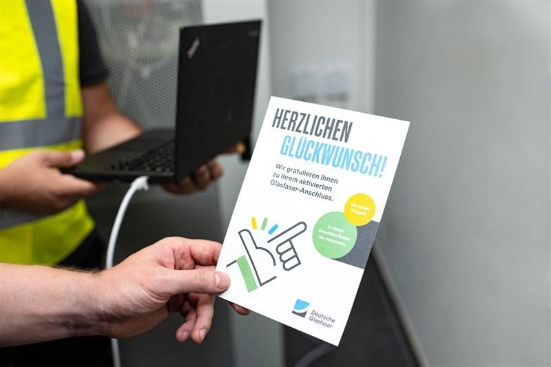 Mann hält Flyer zur Glasfaser in der Hand
