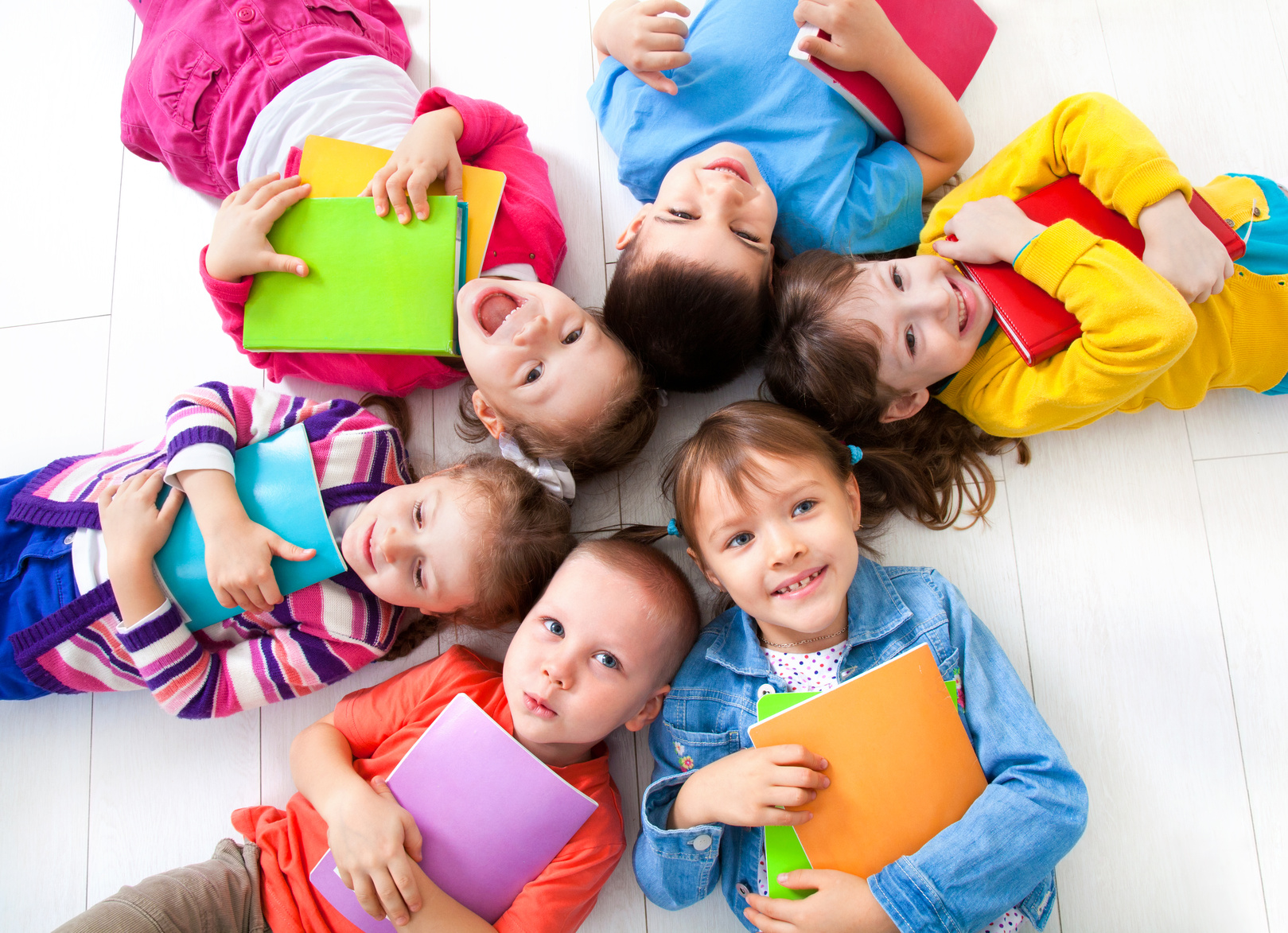 Enfants allongés en cercle et souriant à la caméra