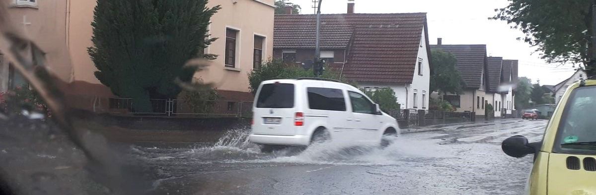 Auto fahrt durch Hochwasser auf der Straße